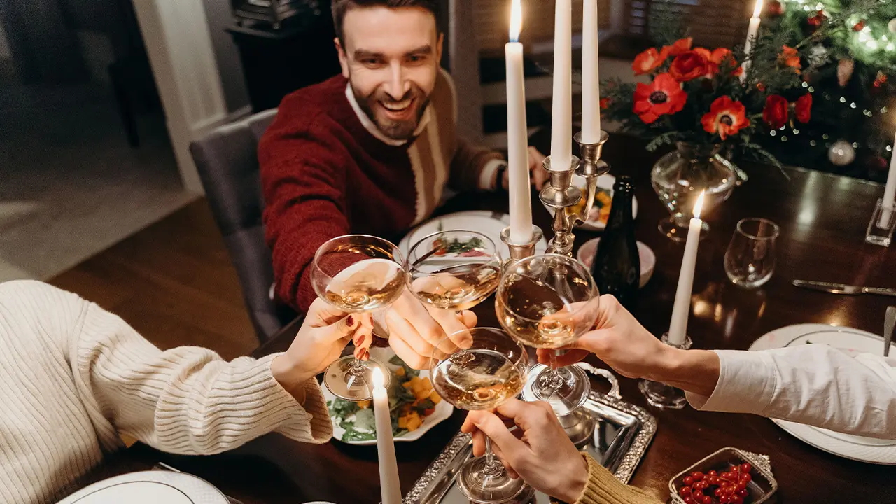 Amis trinquant autour d'un repas de Noël, moment de complicité
